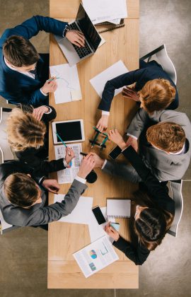 overhead view of business partners doing construction with pencils at table in office